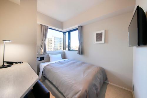 Una habitación de hotel con una cama y una ventana grande. en S-peria Inn Nihombashi Hakozaki, en Tokio