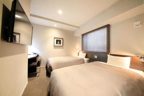 Una habitación de hotel con dos camas, un escritorio y una ventana. en S-peria Inn Nihombashi Hakozaki, en Tokio