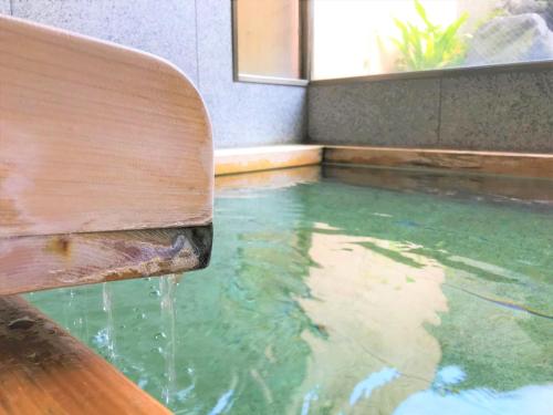 a swimming pool with water coming out of a wooden bench at K's House Hostels - Hakone Yumoto Onsen in Hakone