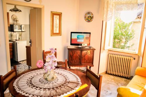 a living room with a table and a television at Appartamento Gubbio Vacanze in Gubbio
