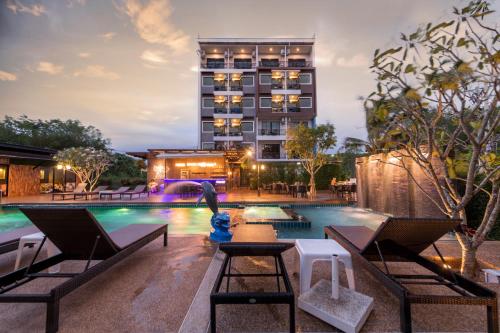 una piscina de hotel con un hotel en el fondo en River Front Krabi Hotel en Krabi