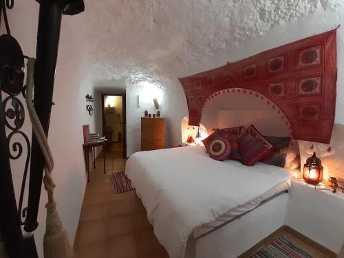1 dormitorio con 1 cama grande y cabecero rojo en Cuevas Galera - Cuevas de la Luz, en Galera