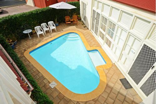 Hi 5 Luxury Holiday Apartments في فيكتور هاربور: اطلالة علوية على مسبح مع كراسي ومظلة