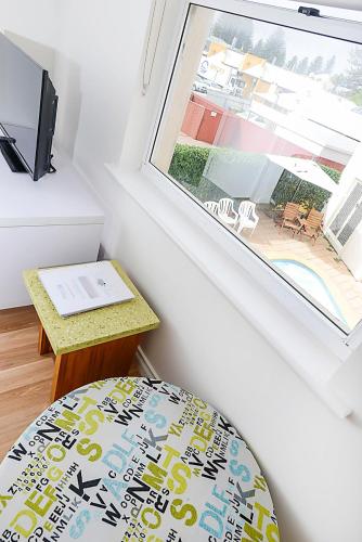 a room with a window and a chair and a table at Hi 5 Victor Harbour Holiday Apartment in Victor Harbor