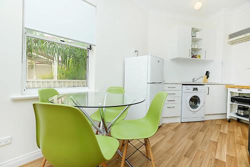 a kitchen with a glass table and green chairs at Hi 5 Victor Harbour Holiday Apartment in Victor Harbor