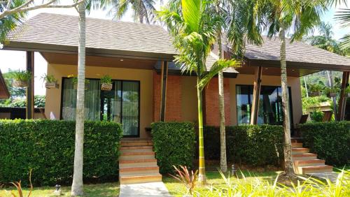 a house with palm trees in front of it at Aonang Hill Krabi-SHA Extra Plus in Ao Nang Beach