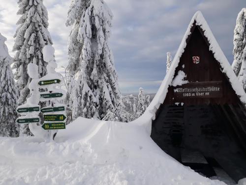 a snow covered cabin with signs in the snow at Ferienwohnungen "Am Schlössel" in Kurort Oberwiesenthal