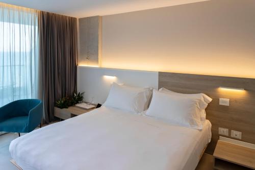 a hotel room with a large bed and a blue chair at Posia Retreat & Spa UNA Esperienze in San Foca