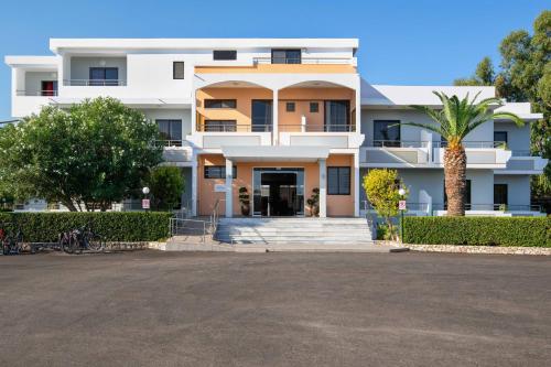 a white building with a palm tree in front of it at Meliton Hotel in Theologos