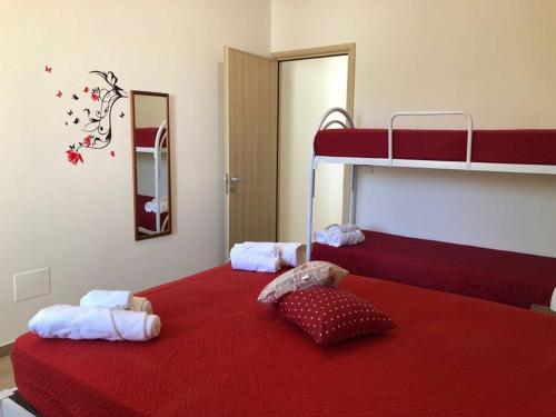 una camera con 2 letti a castello con lenzuola rosse di Home Holidays a Torre Lapillo