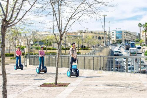 three people riding scooters on a sidewalk at ibis Jerusalem city Center - An AccorHotels Brand in Jerusalem