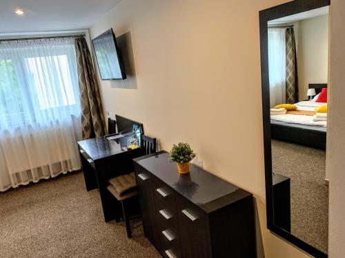Cette chambre comprend un bureau, un miroir et un lit. dans l'établissement Mocca House, à Raszyn