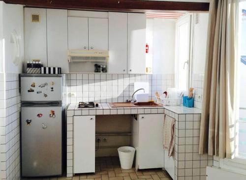  La cuisine est équipée de placards blancs et d'un réfrigérateur. dans l'établissement Best located flat in Saint-Germain-des-Prés, à Paris
