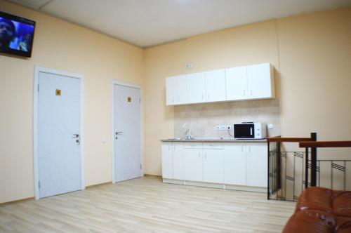 pusta kuchnia z białymi szafkami i kuchenką mikrofalową w obiekcie Хостел на Баварии w Charkowie