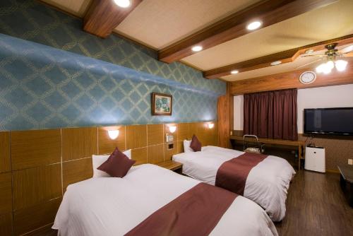 Habitación de hotel con 2 camas y TV de pantalla plana. en Sejour Fujita en Hiroshima