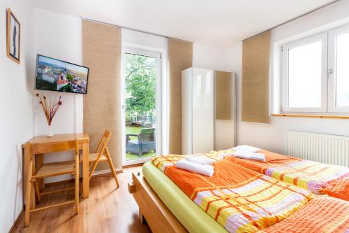 two beds in a room with a desk and window at Ubytování Bezchlebovi in Český Krumlov