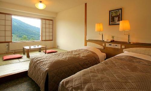 a hotel room with two beds and a window at Madarao Kogen Hotel in Iiyama