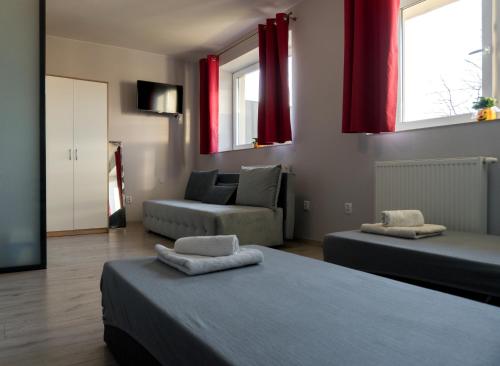 a room with two beds and a couch and red curtains at Pensjonat Lubianka in Starachowice