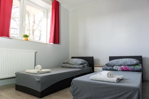 two beds in a room with red curtains at Pensjonat Lubianka in Starachowice