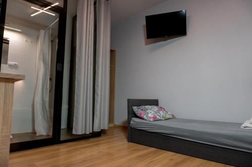 a bedroom with a bed and a tv on the wall at Pensjonat Lubianka in Starachowice