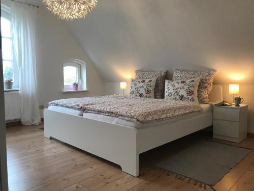 a bedroom with a white bed with pillows and a chandelier at Hendreich's Hof in Boitin Resdorf