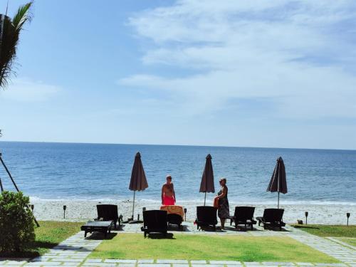 a group of people standing on the beach with umbrellas at Mae Pim Dream Condo in Mae Pim