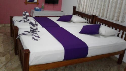 two beds with purple and white blankets and pillows at SA Village in Dambulla