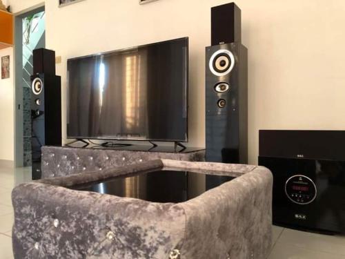 a living room with a tv and a couch with speakers at Villa Bunmark in Sirindhorn