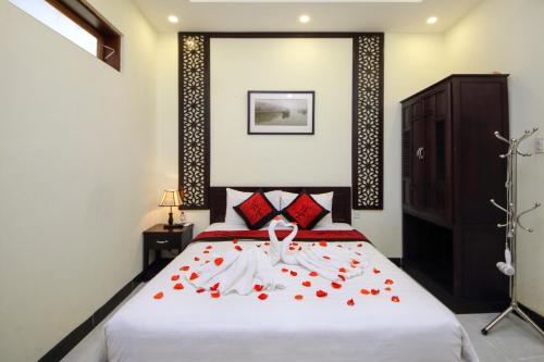 a bedroom with a bed with red roses on it at Fireworks Homestay in Hoi An