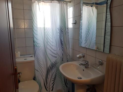 een badkamer met een wastafel, een toilet en een douchegordijn bij Hotel Ionion in Kyllini