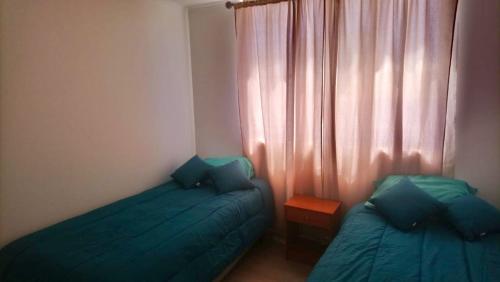 a bedroom with two beds and a window with curtains at Cómodo departamento en el centro de Casablanca in Casablanca