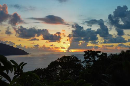a sunset over the ocean with trees in the foreground at Sunset Bay Apartment in Glacis