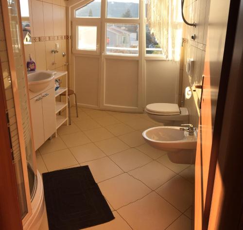 a bathroom with two sinks and a toilet and a window at Lipovac resort Ficus in Bilice