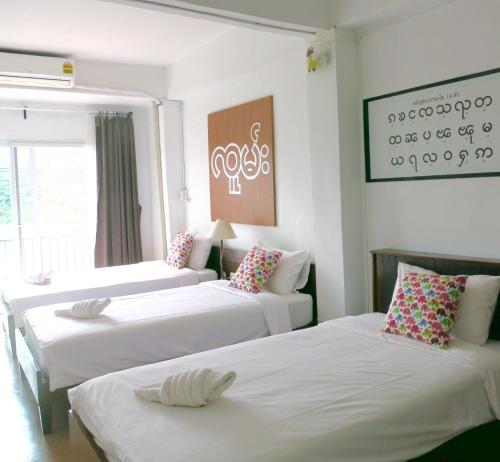 a room with three beds with white sheets and pillows at Yoont Hotel in Ban Khun Yuam