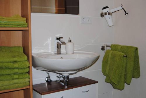 a bathroom with a white sink and green towels at Ferienwohnung Kirchbergblick in Hackenheim