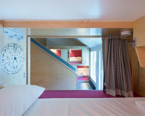 a room with a bed and a staircase with a mirror at Pangea Pod Hotel in Whistler