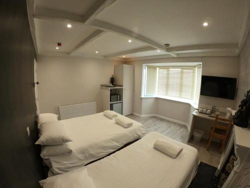 Habitación con 2 camas, escritorio y TV. en Debden Guest House, en Hillingdon