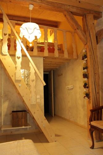 a wooden staircase in a house with a chandelier at Ch'tit Jura in Les Moussières