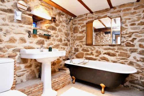 La salle de bains en pierre est pourvue d'un lavabo et d'une baignoire. dans l'établissement Cottage, à La Châtaigneraie