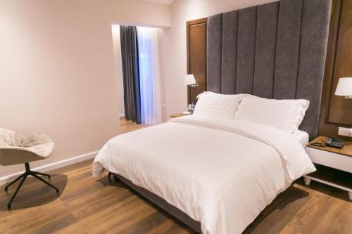 a bedroom with a large white bed and a chair at Arberia Palace Hotel in Fushë-Milot