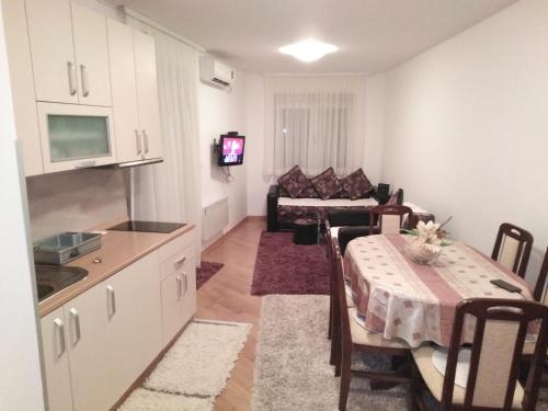 FEEL LIKE HOME في Vrnjačka Banja: مطبخ وغرفة معيشة مع طاولة وأريكة