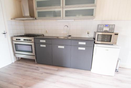 uma cozinha com um lavatório, um fogão e um micro-ondas em Vissershuisje aan de waddenzee em Paesens