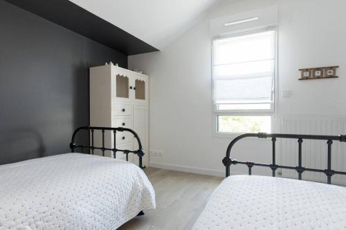 a white bedroom with a bed and a refrigerator at Appartement 4 étoiles vue mer et bord de plage Chez Odette in Saint Malo