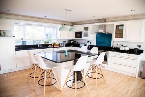 a kitchen with white cabinets and a table and chairs at 2 Princes Cottages in Plymouth
