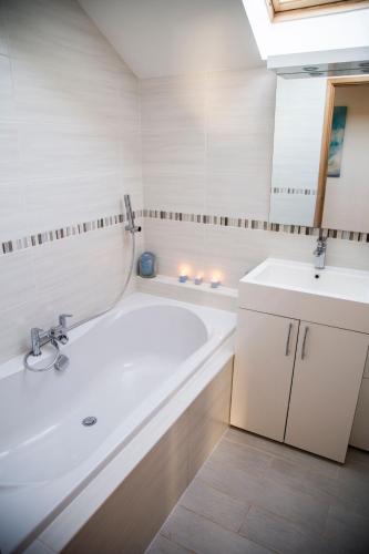 a white bathroom with a tub and a sink at 2 Princes Cottages in Plymouth