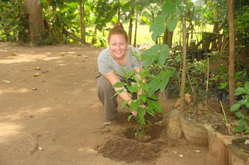 a woman kneeling next to a small tree at HOMESTAY CAMPING ANURADHAPURA in Anuradhapura