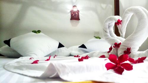 two white swans sitting on a bed with flowers at Eagle Homestay in Tangalle