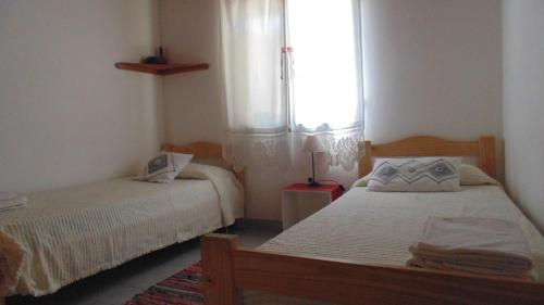 two beds in a room with a window at Casa Las Calas in Puerto Madryn