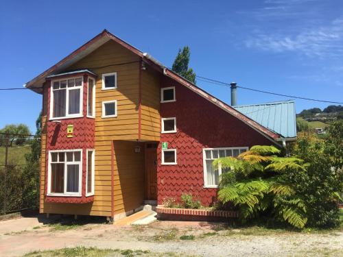 una casa pintada de rojo y amarillo en Cabañas Encantos, en Castro