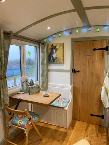 Willowbank shepherds hut في تونتون: غرفة صغيرة مع طاولة ونافذة